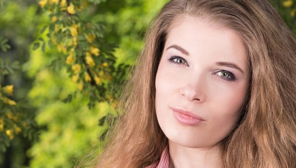Horizontal closeup portrait of a beautiful young woman with her hair in nature - Photo, Image