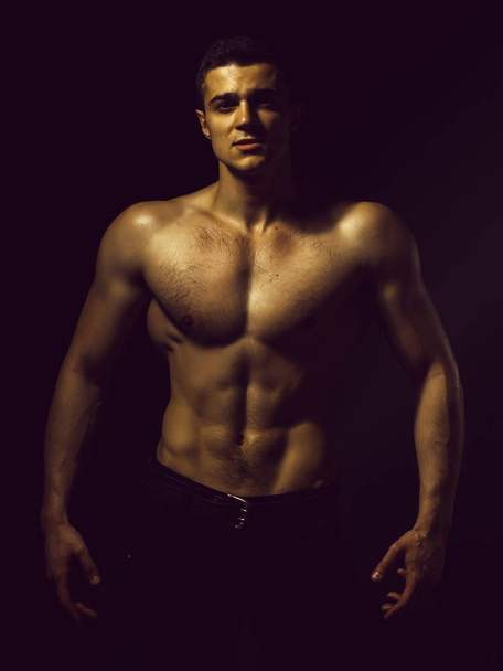 Joven hombre guapo con el cuerpo musculoso con el pecho desnudo y el torso posando en el estudio sobre fondo negro
 - Foto, Imagen