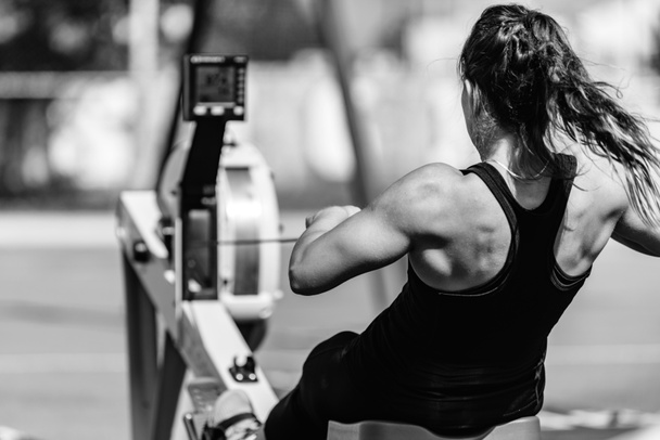 Female athlete on rowing machine on cross competition. - Photo, Image