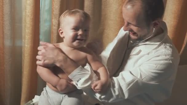 The doctor visits the baby patient at home. Happy Baby with stethoscope - Video, Çekim