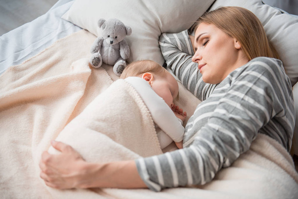 Abbastanza mamma a riposo con bambino su biancheria da letto
 - Foto, immagini