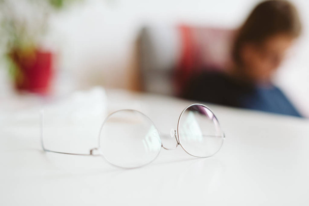 Óculos espetaculares na mesa com silhueta de mulher na parte de trás
 - Foto, Imagem