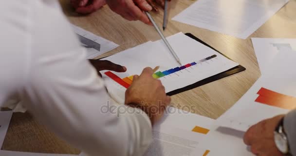 Вид зверху на багатоетнічні руки з олівцями, що аналізують і займаються паперовими документами, графіками, фінансовими звітами і графікою на білому дерев'яному столі. Бізнес команда працює
. - Кадри, відео