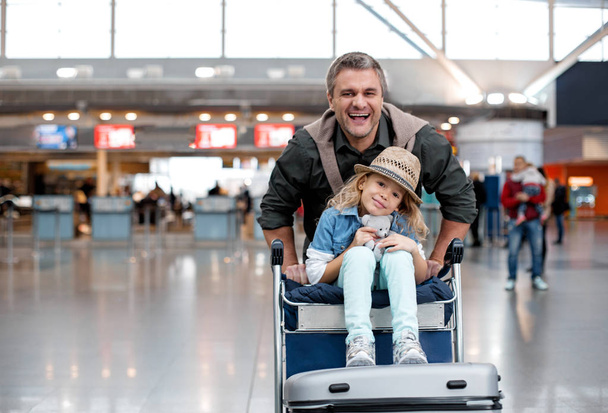 Cheerful adult man and little girl are playing in terminal - Foto, imagen