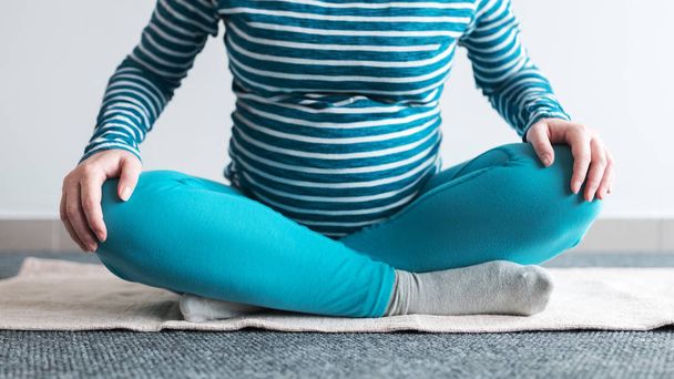 Zwangere vrouw het beoefenen van yoga oefening thuis. - Foto, afbeelding