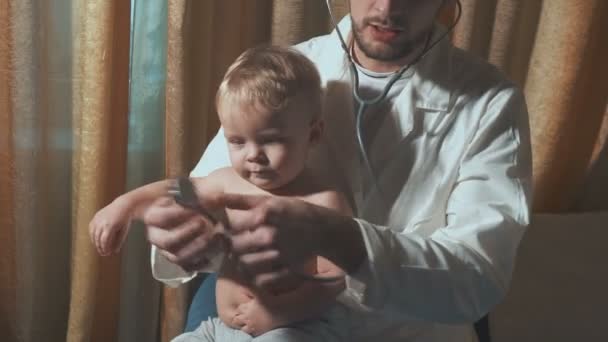 The doctor visits the baby patient at home. Baby with stethoscope - Séquence, vidéo