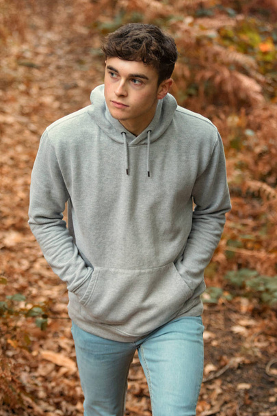 Teenage boy walking though a woodland in autumn - Valokuva, kuva