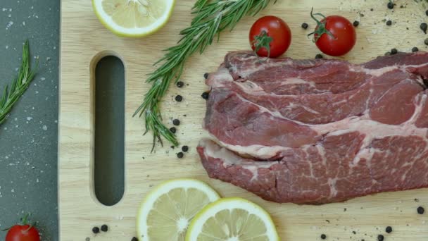 čerstvé syrové hovězí steak s kořením na dřevěné desce - Záběry, video
