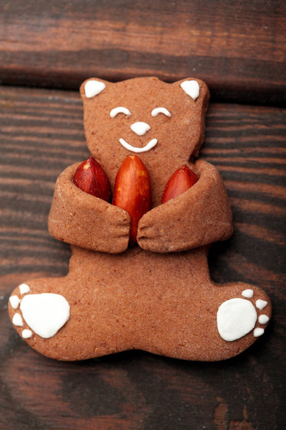 Funny Gingerbread bear cookies hold in claws thre peanuts. Top view Closeup.Funny image.Happy bear - Photo, Image