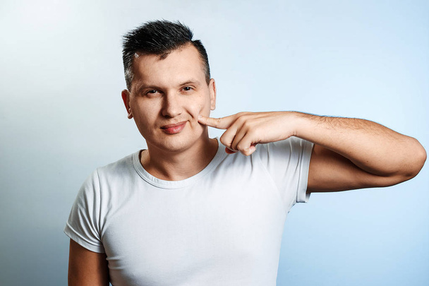 Portrait of a white man on a light background, gesture finger to cheek, Italian gesture delicious. The concept of body language, expression of emotions, reaction. - Fotoğraf, Görsel