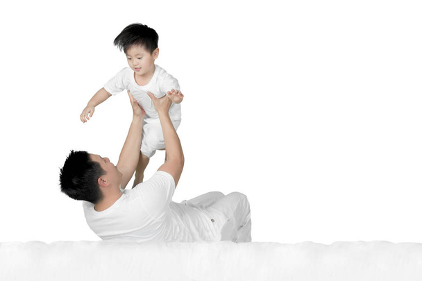 Young man lifting his son on the bed - Фото, зображення