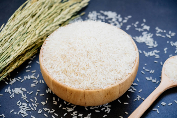 Ruwe jasmijn rijst in houten kom en lepel met graan en zaad - Foto, afbeelding