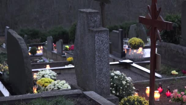 Grabsteine und Kerzen brennen am Abend in Waldnähe. 4k - Filmmaterial, Video