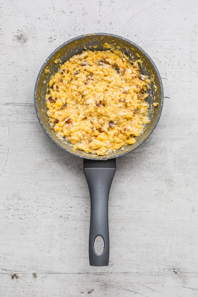 Ham and eggs. Scrambled eggs with bacon in ceramic pan - Photo, Image