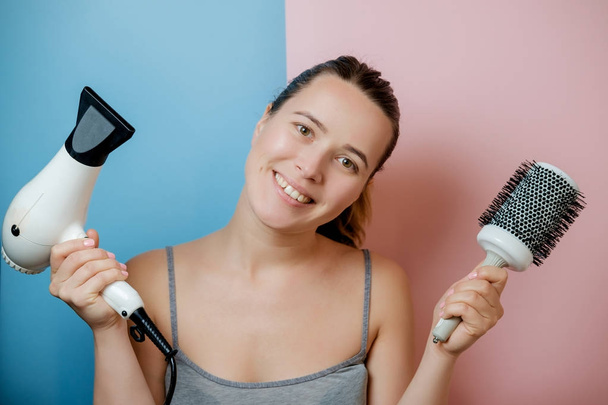 Young woman with hair dryer and comb. Studio shot - Φωτογραφία, εικόνα
