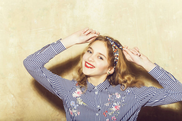Cheerful pretty girl in blue striped shirt ties headband - Fotó, kép