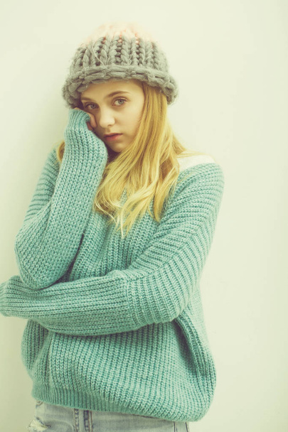 Pretty young girl with blond hair in fashionable sweater, hat - 写真・画像