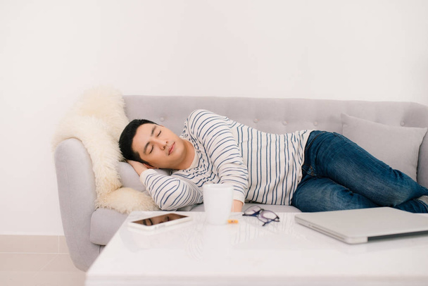 Молодий красивий азіатський чоловік спить на дивані
. - Фото, зображення