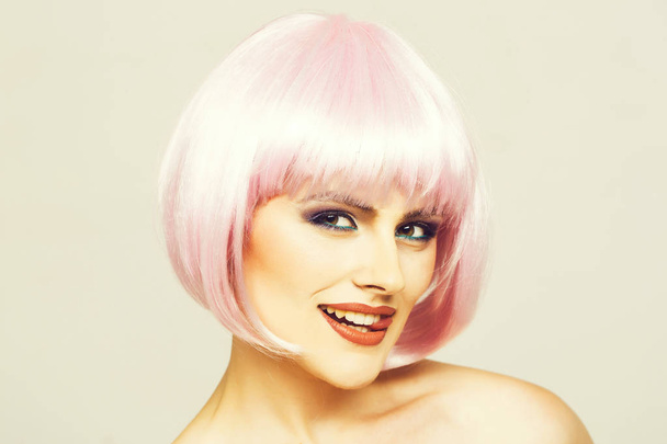 sexy glamour girl or woman with fashionable makeup on pretty smiling face and short hairstyle or pink wig in studio on light background - Foto, afbeelding