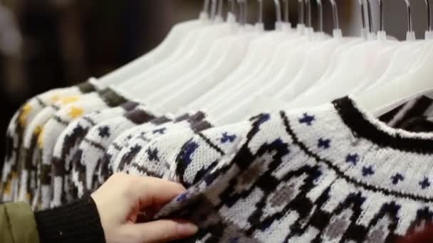 Woman choosing a pullover at shop in shopping centre - Footage, Video
