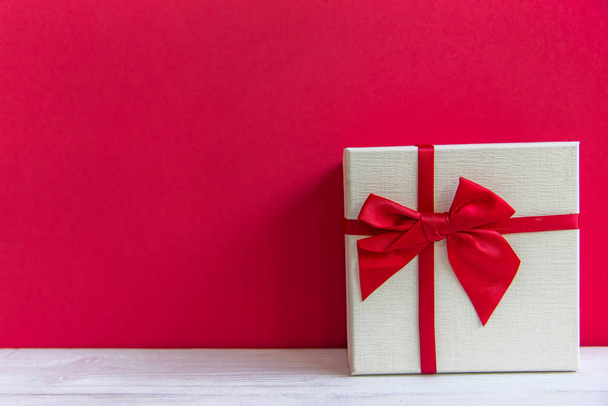 Valentine day white gift box with a red bow on red wall background, copy space. Valentine Concept. - Photo, Image