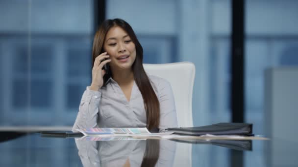 4K Cheerful businesswoman in the office talking on phone and looking at paperwork. - Séquence, vidéo
