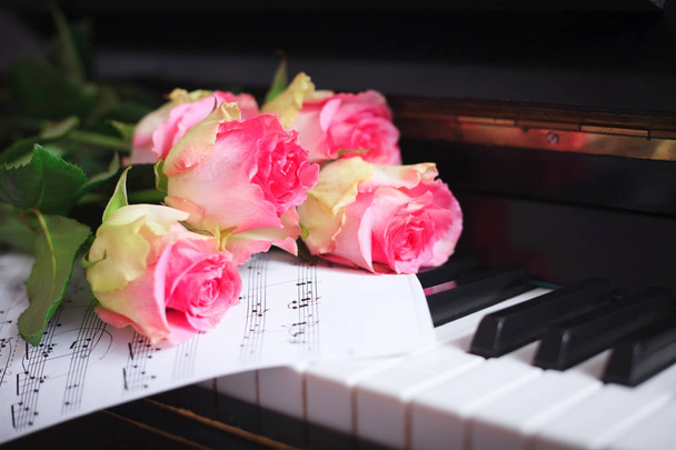Un bouquet de roses roses et des notes sur le clavier du piano
. - Photo, image