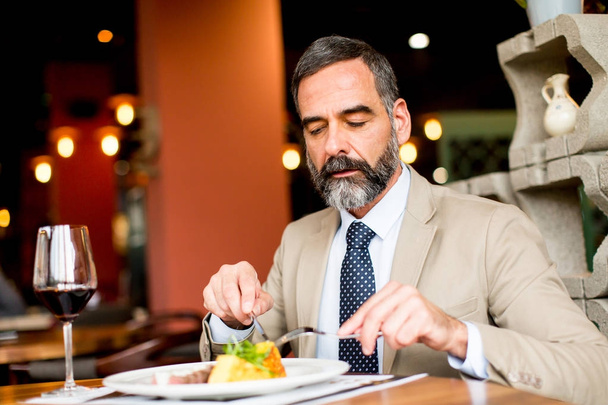 Portrait of senior man eating lunch in restaurant - Foto, Imagem