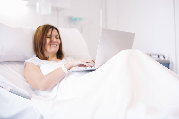 vrouw ziek met laptop in het ziekenhuis - Foto, afbeelding