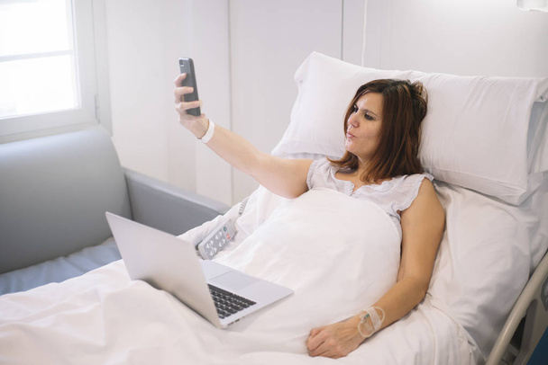 ill woman with Smartphone and laptop in the hospital - Foto, immagini
