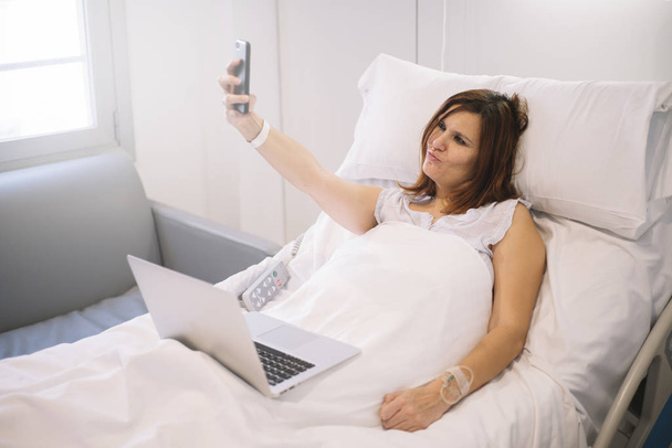 ill woman with Smartphone and laptop in the hospital - Fotó, kép