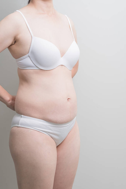 Fat overweight woman standing on grey  background, asian - Fotó, kép