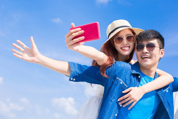 couple taking selfie happily with the blue sky on background - Foto, afbeelding