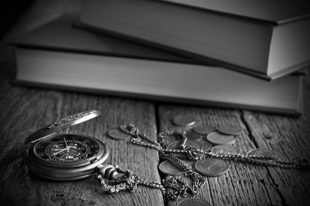 Immagine in bianco e nero di un antico orologio da tasca e vecchie monete su una superficie ruvida del tavolo
.  - Foto, immagini