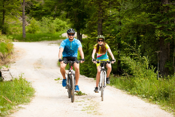 ACTIVE Young couple biking on a forest road in mountain on a spr - Photo, Image