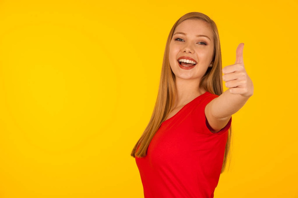 Beautiful young woman in red t shirt over yellow background show - Foto, imagen
