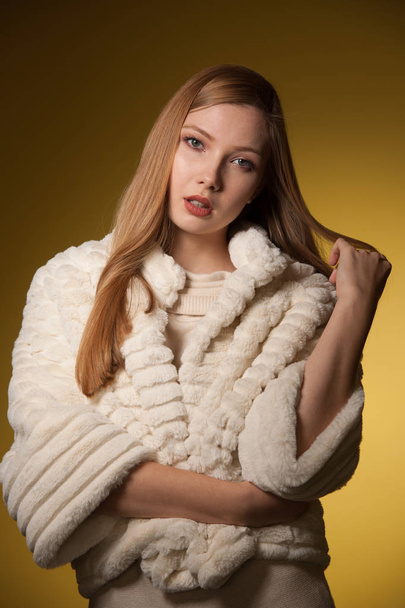 Beauty portrait of woman in fur winter jacket over yellow backgr - Valokuva, kuva