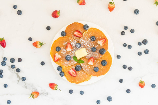 gesundes Frühstücksset mit Pfannkuchen Blaubeeren und Erdbeeren auf Steintischhintergrund - Foto, Bild