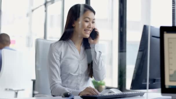 4K Businesswoman working on computer in office getting good news from phone call - Séquence, vidéo