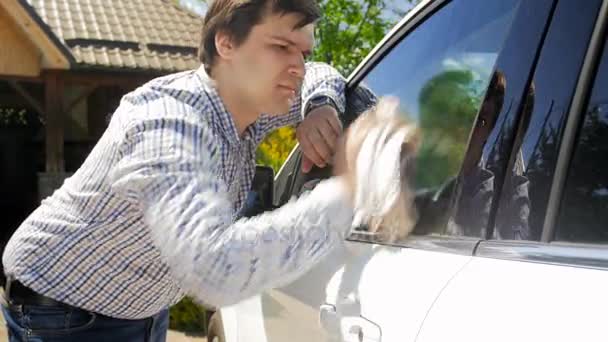 4k footage of young man cleaning his car with cloth at backyard - Séquence, vidéo