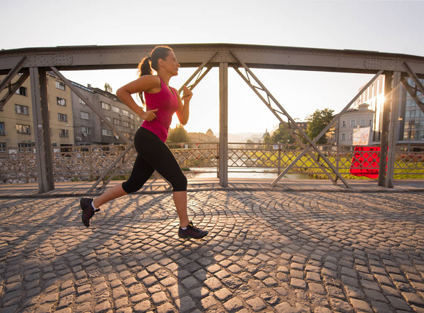 woman jogging across the bridge at sunny morning - Fotó, kép