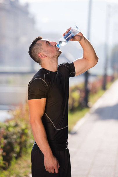 человек пьет воду из бутылки после пробежки
 - Фото, изображение