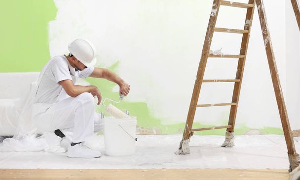 peintre homme au travail prend la couleur avec un pinceau à rouleaux de
 - Photo, image