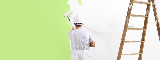 pintor hombre en el trabajo con un rodillo de pintura, pintura de pared verde col
 - Foto, Imagen