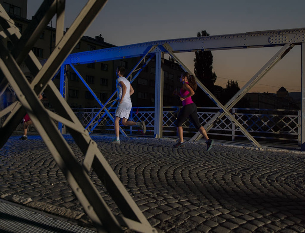 portrait of couple jogging across the bridge in the city - Fotografie, Obrázek