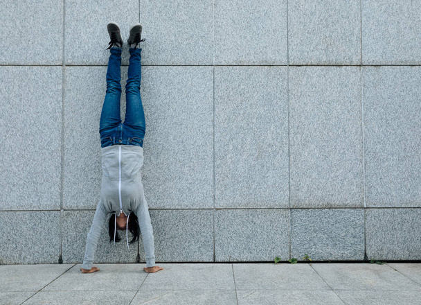 Young woman doing a handstand against wall - Fotografie, Obrázek