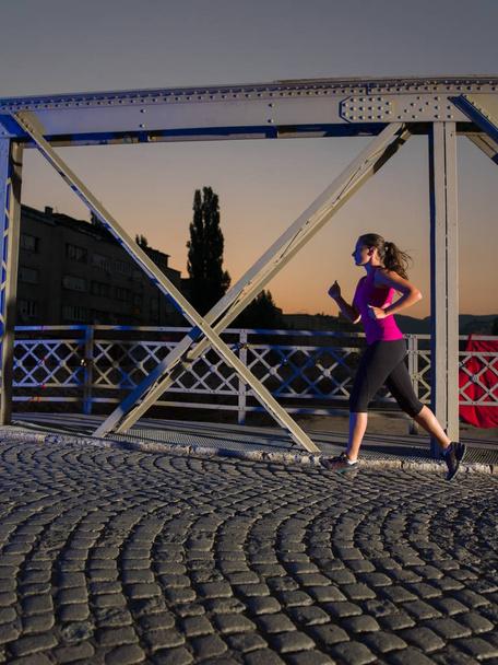 woman jogging across the bridge in the city - Foto, Imagen