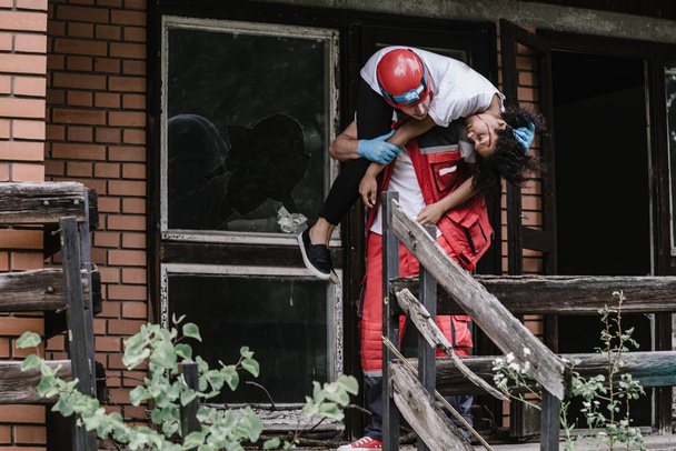Ratowanie pracownik przeprowadzenie uszkodzonego domu ofiary katastrofy - Zdjęcie, obraz