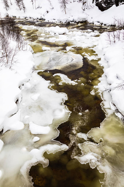 Een streaming winter rivier tussen het ijs en de sneeuw in de bergen van het Setesdal, Noorwegen - Foto, afbeelding