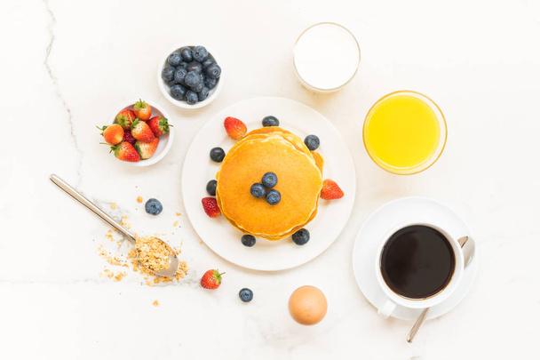 Healthy Breakfast set with Pancake and Granola with blueberry and strawberry and black coffee , Milk and Orange juice on white stone table background - Foto, Imagem